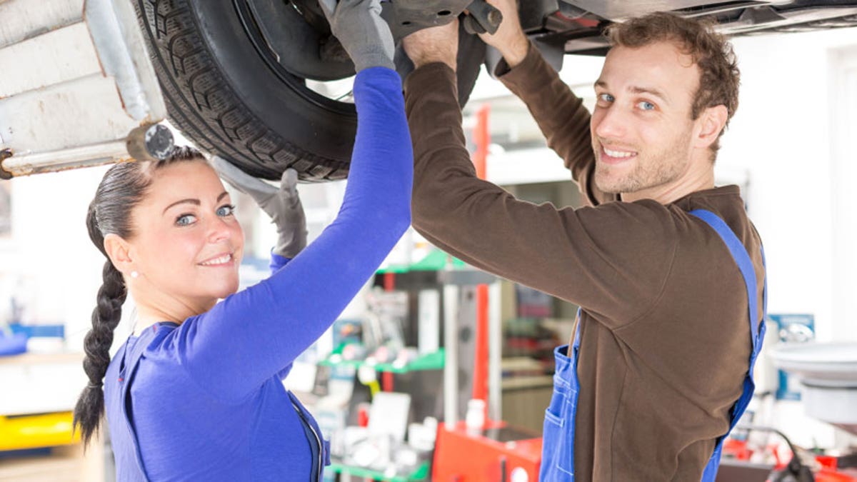 Two mechanics repairing a car in hydraulic lift