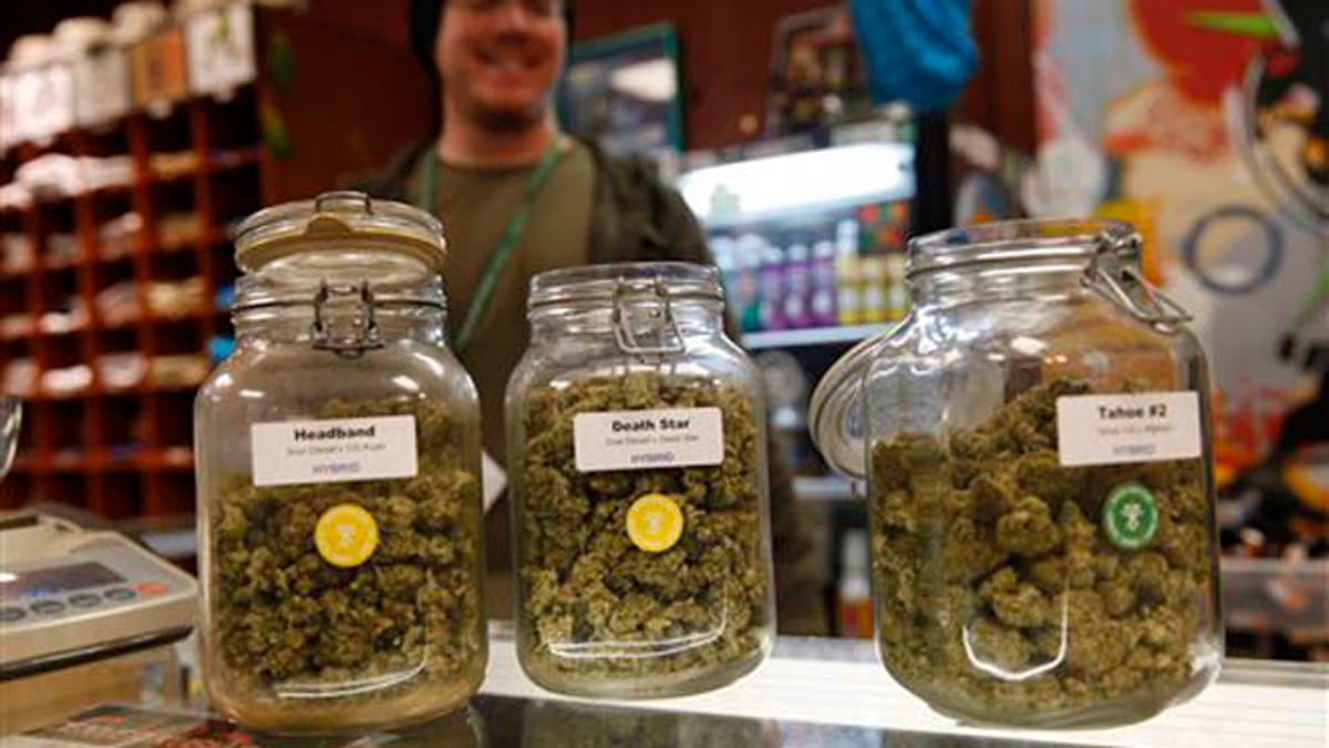 Jars of marijuana buds sit on the counter at the Denver Kush Club early Friday, Nov. 27, 2015, in north Denver. More than two dozen customers took advantage of a new Colorado holiday tradition of marijuana shops drawing customers with discounted weed and holiday gift sets. (AP Photo/David Zalubowski)