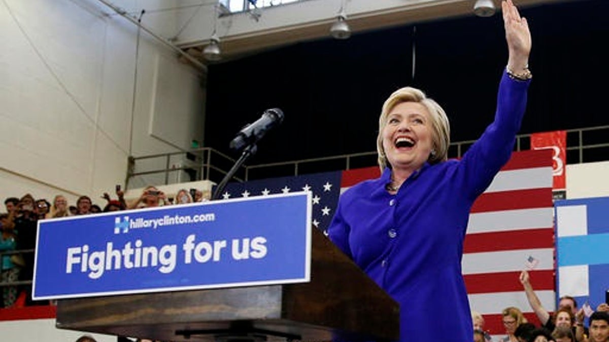 Democratic presidential candidate Hillary Clinton, left, reacts as she takes the stage at a rally, Monday, June 6, 2016, in Long Beach, Calif. Eight years after conceding she was unable to "shatter that highest, hardest glass ceiling," Hillary Clinton is embracing her place in history as she finally crashes through as the presumptive Democratic presidential nominee. (AP Photo/John Locher)