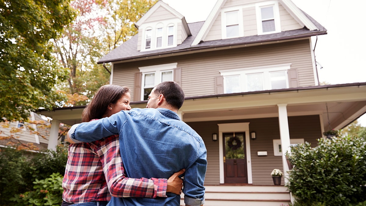 Couple arm-in-arm in front of house