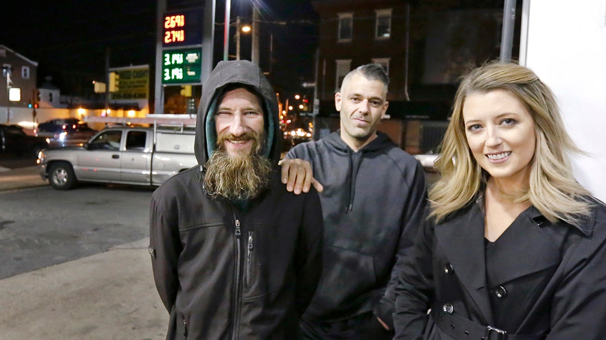 In this Nov. 17, 2017, photo, Johnny Bobbitt Jr., left, Kate McClure, right, and McClure's boyfriend Mark D'Amico pose at a Citgo station in Philadelphia. When McClure ran out of gas, Bobbitt, who is homeless, gave his last $20 to buy gas for her. McClure started a Gofundme.com campaign for Bobbitt that has raised more than $13,000. (Elizabeth Robertson/The Philadelphia Inquirer via AP)