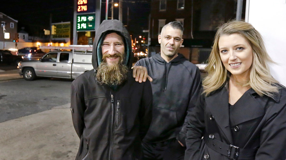 In this Nov. 17, 2017, photo, Johnny Bobbitt Jr., left, Kate McClure, right, and McClure's boyfriend Mark D'Amico pose at a Citgo station in Philadelphia. When McClure ran out of gas, Bobbitt, who is homeless, gave his last $20 to buy gas for her. McClure started a Gofundme.com campaign for Bobbitt that has raised more than $13,000. (Elizabeth Robertson/The Philadelphia Inquirer via AP)