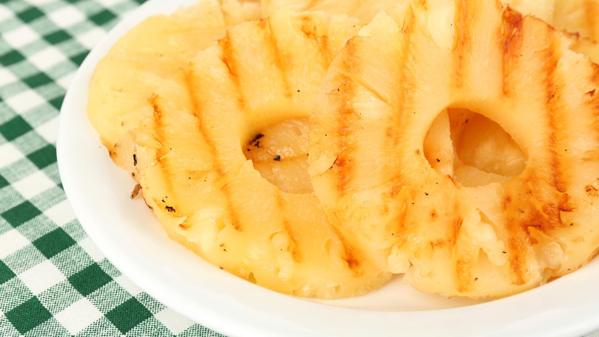 Juicy grilled pineapple on plate on table close-up