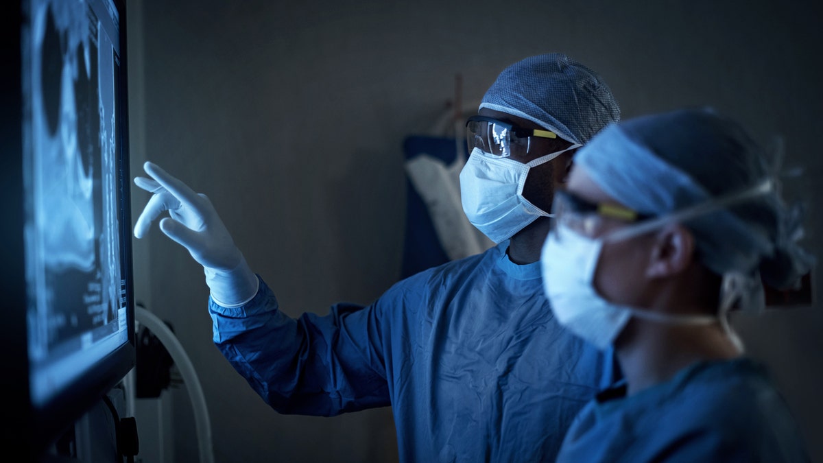 Shot of two surgeons analyzing a patientâs medical scans during surgery