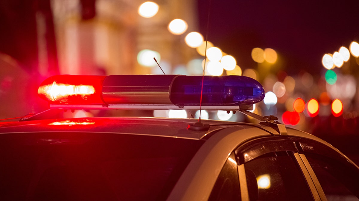 Red light flasher atop of a police car. City lights on the background. 