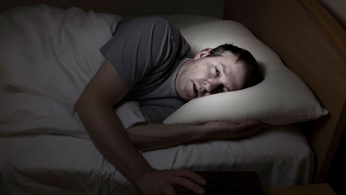 man lies awake with insomnia