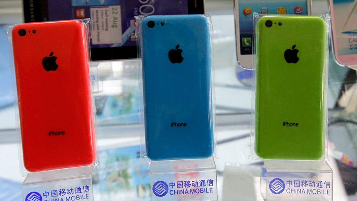 Apple's iPhone 5Cs phones are displayed on racks bearing the logo of China Mobile, at a mobile phone shop in Beijing December 23, 2013. Apple Inc said it has signed a long-awaited agreement with China Mobile Ltd to sell iPhones through the world's biggest network of mobile phone users. REUTERS/Kim Kyung-Hoon (CHINA - Tags: BUSINESS TELECOMS) - RTX16S8J