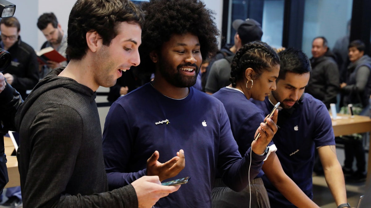 An Apple sales associate speaks with a customer waiting to purchase a new iPhone X in New York, U.S., November 3, 2017.  REUTERS/Lucas Jackson - RC1E691B9A00