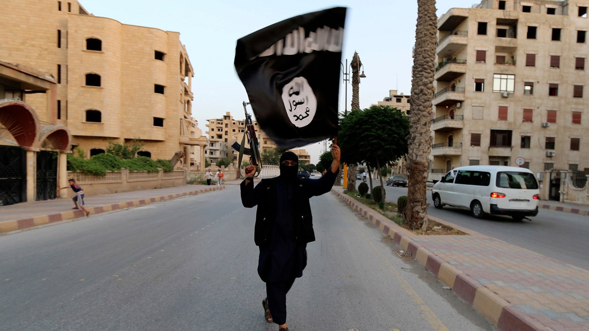 A member loyal to the Islamic State in Iraq and the Levant (ISIL) waves an ISIL flag in Raqqa June 29, 2014. The offshoot of al Qaeda which has captured swathes of territory in Iraq and Syria has declared itself an Islamic 