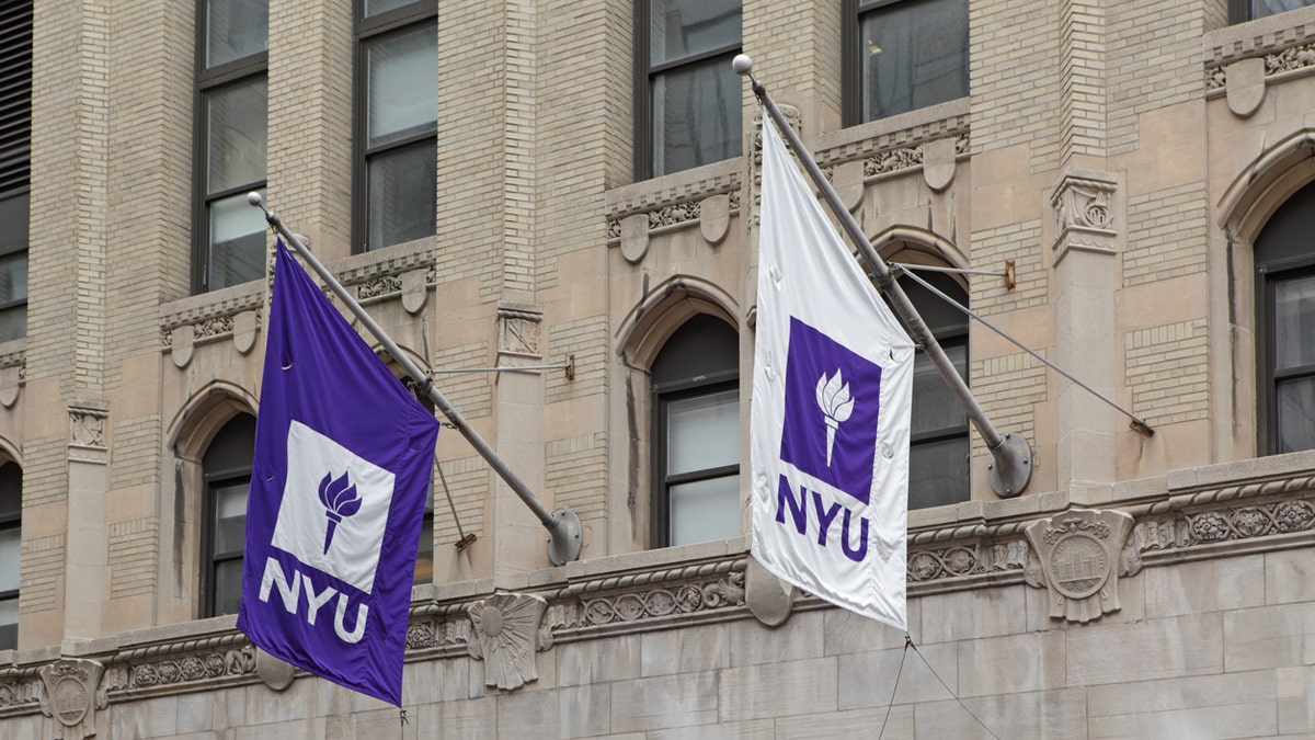 New York, NY, USA - June 3, 2015: Purple and white NYU flags hang from a New York University building on West 4th Street in Manhattan. In 1965, graphic artist Tom Geismar designed the torch logo now used on all NYU flags.