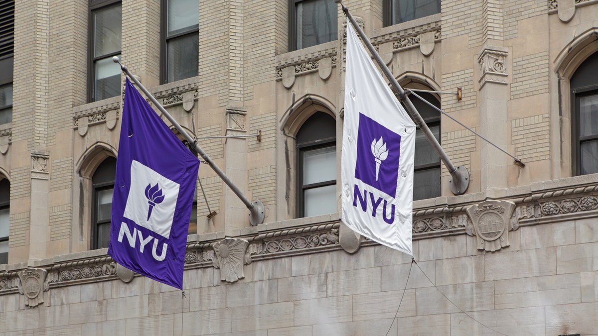 New York, NY, USA - June 3, 2015: Purple and white NYU flags hang from a New York University building on West 4th Street in Manhattan. In 1965, graphic artist Tom Geismar designed the torch logo now used on all NYU flags.
