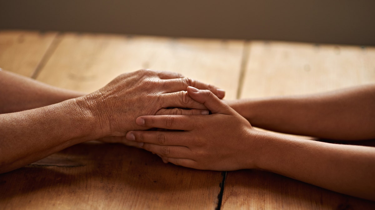 A cropped shot of a woman holding a loved one's hand in support