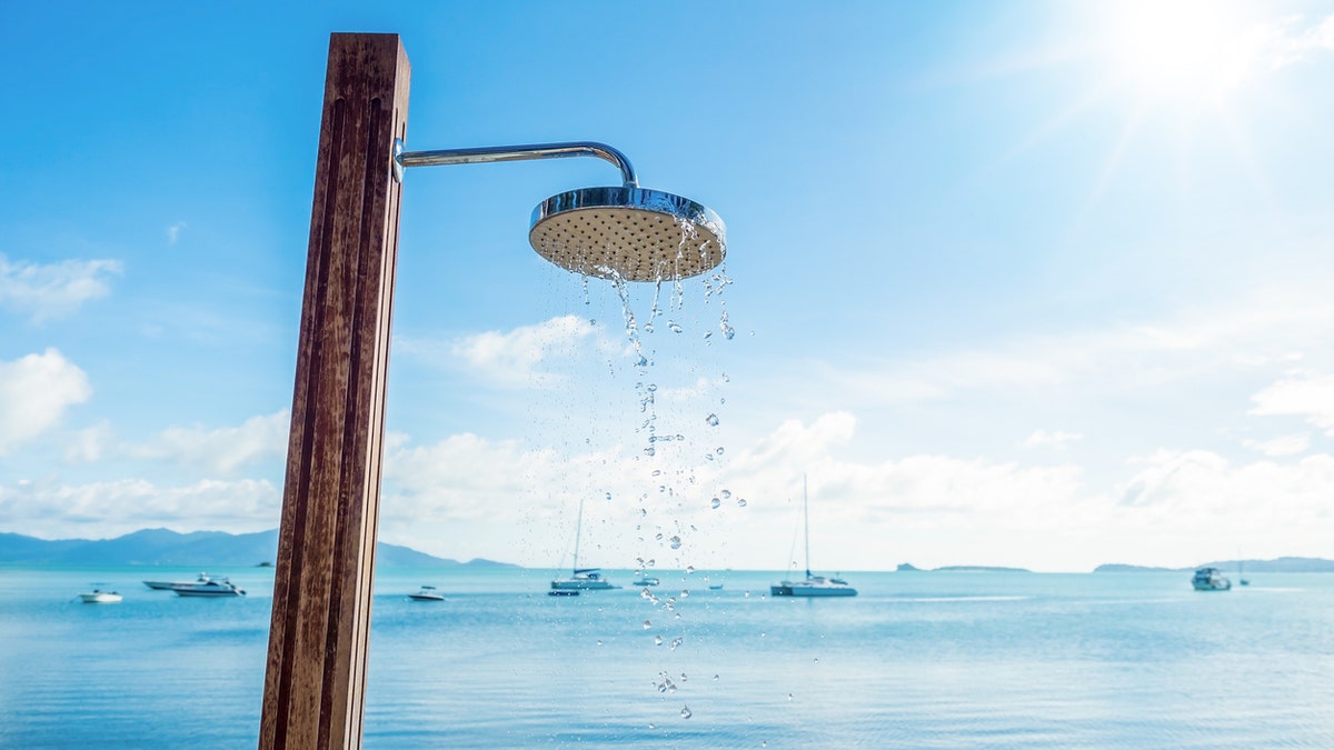 shower head with water droplets on seashore and blue sky background