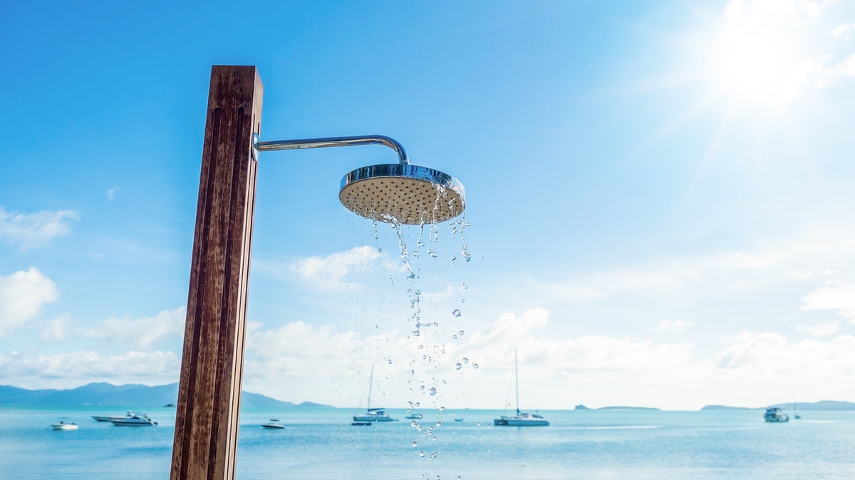 shower head with water droplets on seashore and blue sky background