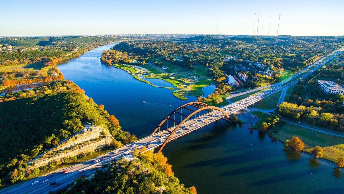 Aerial Pennybacker Bridge 360 Bridge From the Air as the leaves change colors and fall and the seasons change in central Texas. Fall turns to winter and Austin , Texas glows with bright colors of Fall and green and the Texas hill country looks amazing. This aerial breathtaking image of the Pennybacker Bridge built in 1984 and completes the Austin Vibe of West Texas Hill Country 