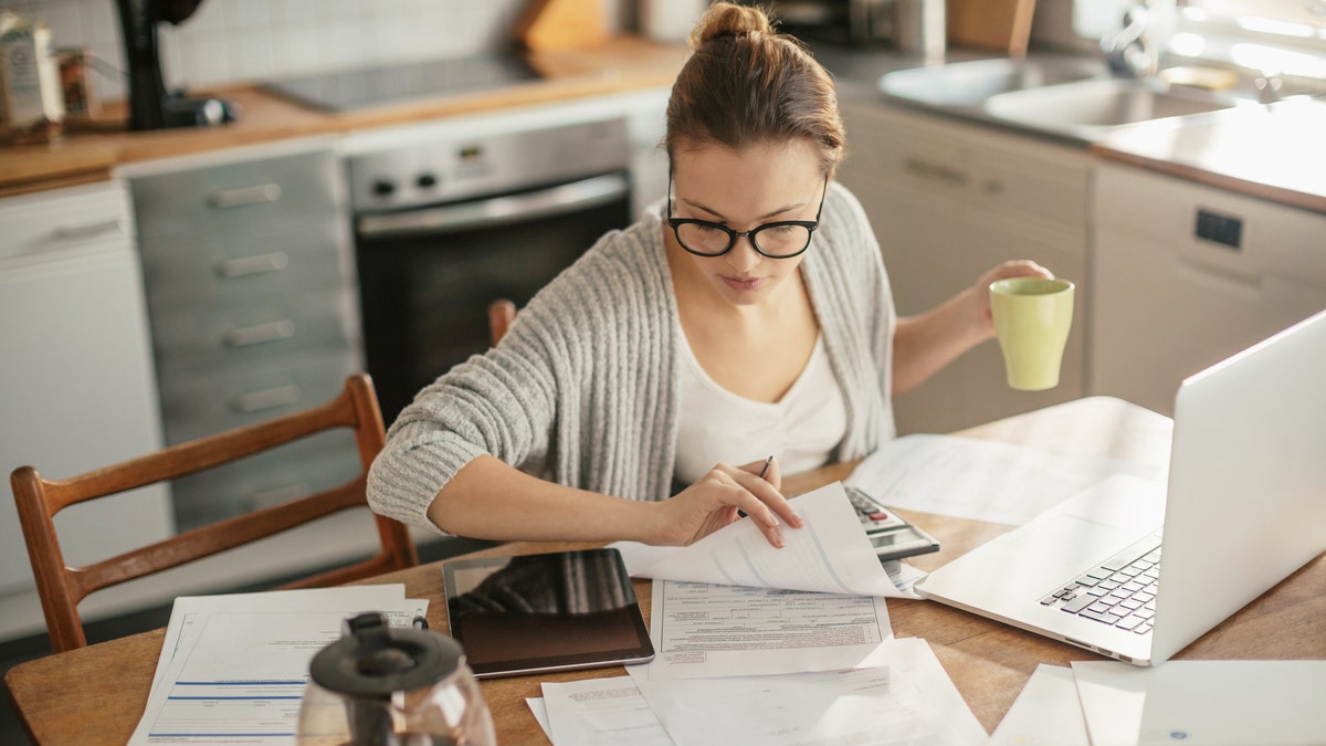 Close up of a young woman sitting in kitchen and going through her financials