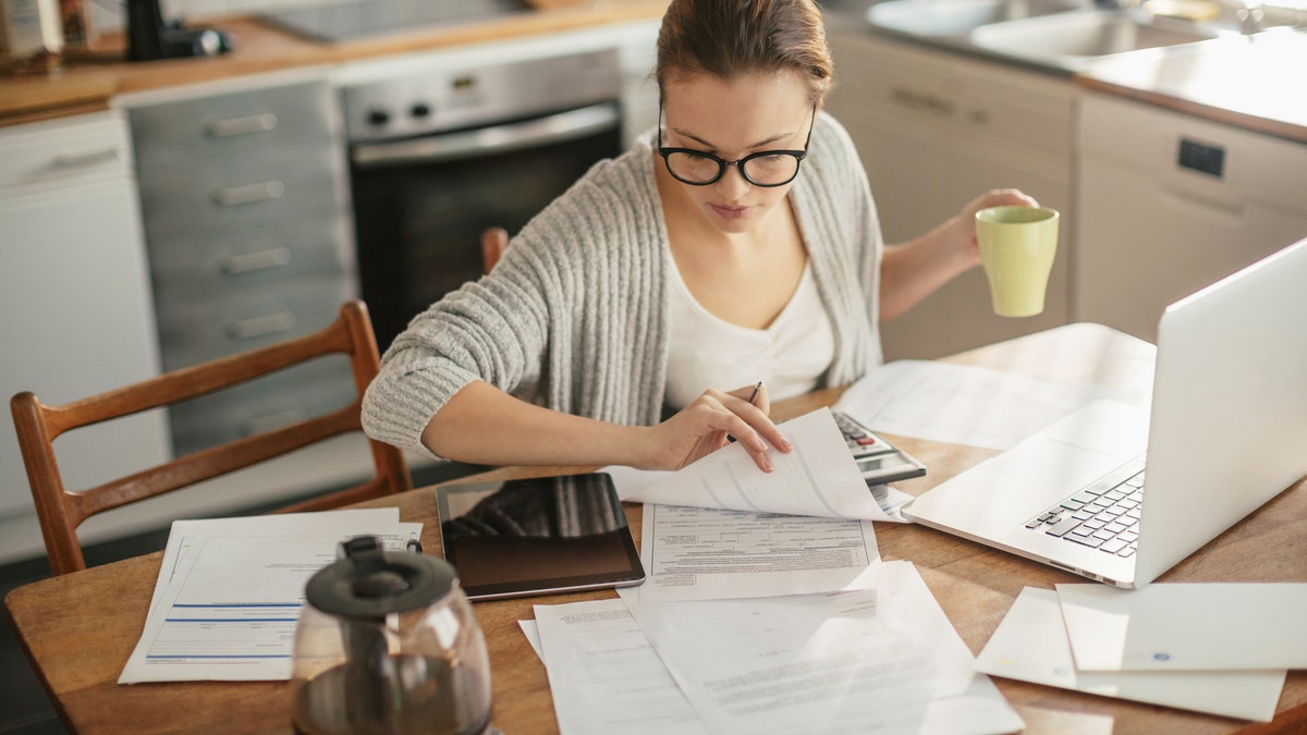 Close up of a young woman sitting in kitchen and going through her financials