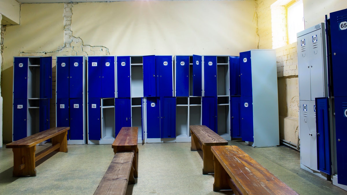 Photo shows generic locker room with blue lockers in a gym