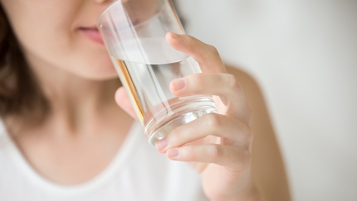 Happy beautiful young woman drinking water