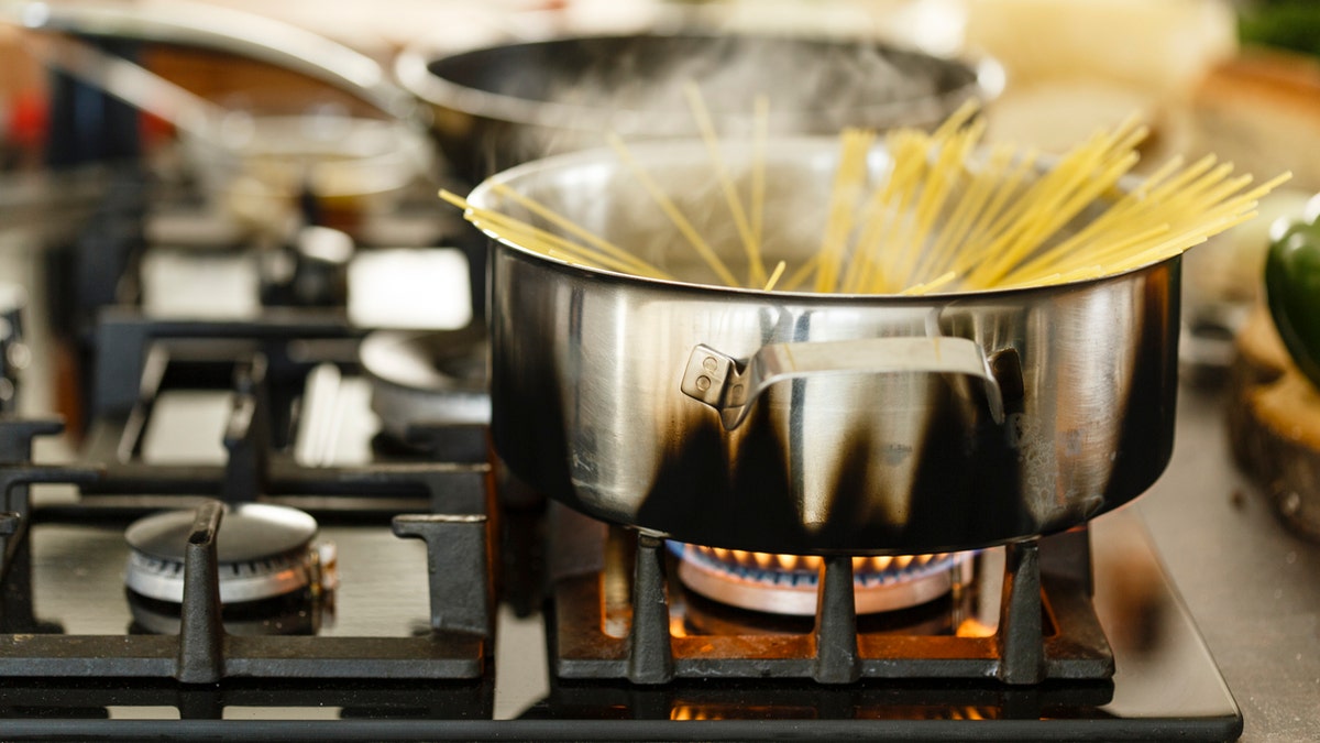 Spaghetti in boiling water on gas stove