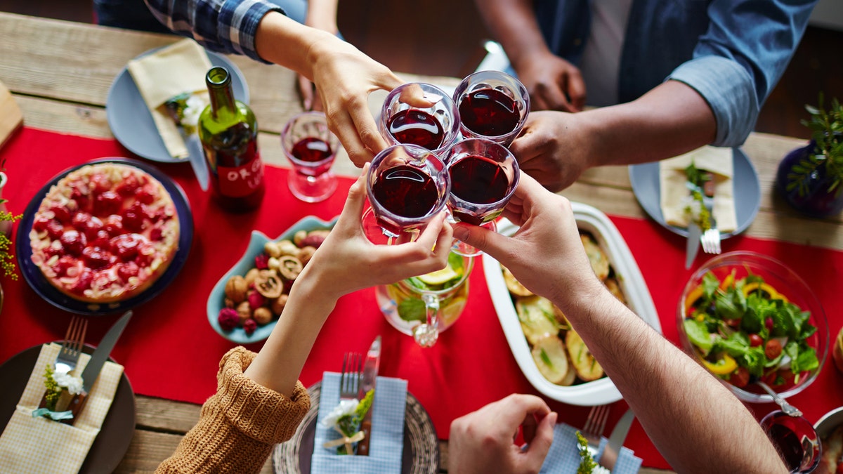 Friends toasting with red wine over served table