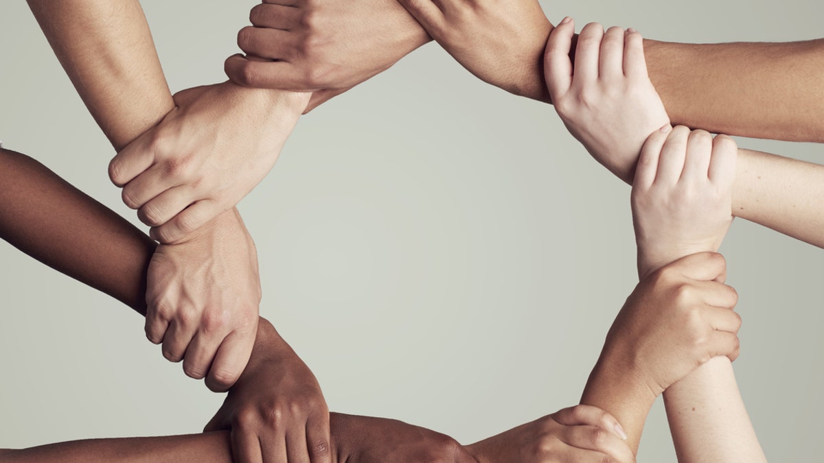 Cropped shot of a diverse group of unidentifiable people holding hands in a circle