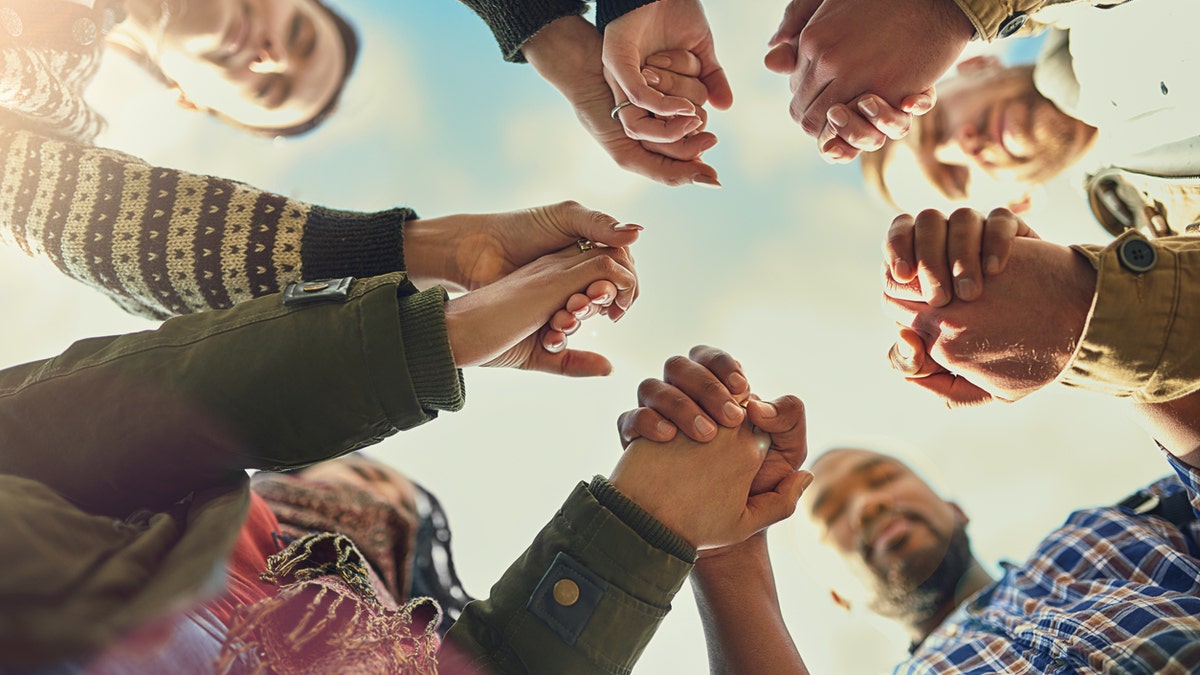 Shot of a group of friends putting their hands together in prayer