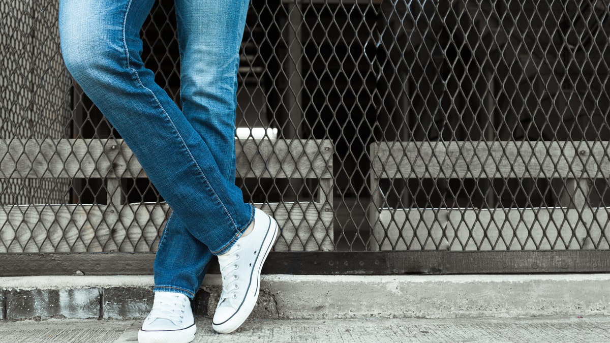 Woman posing in jeans against the fence.
