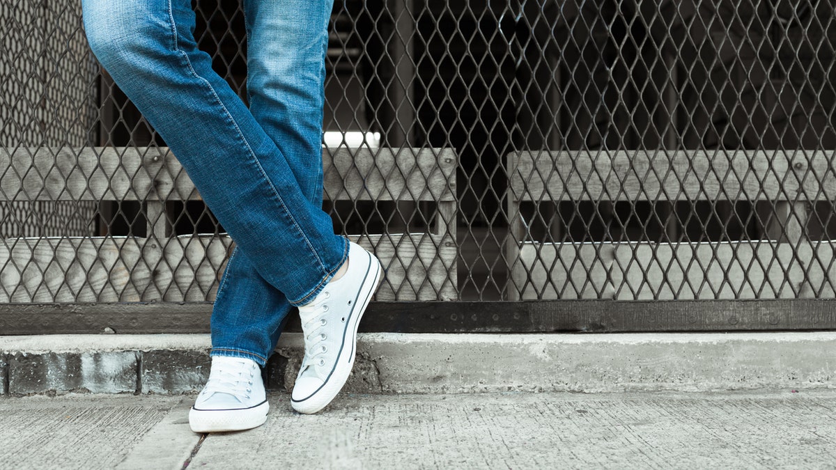 Woman posing in jeans against the fence.