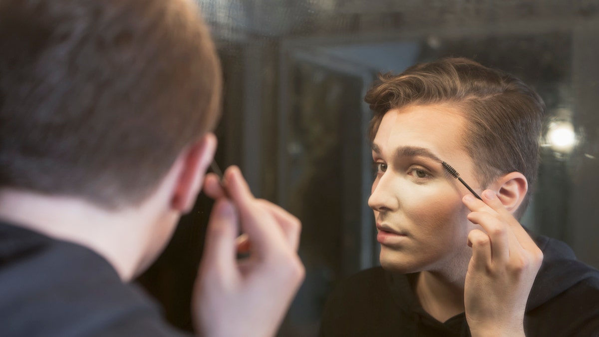 boy applying makeup istock