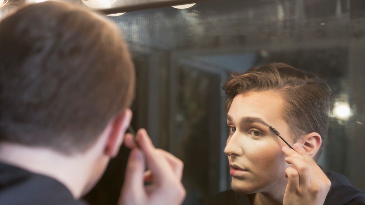 boy applying makeup istock