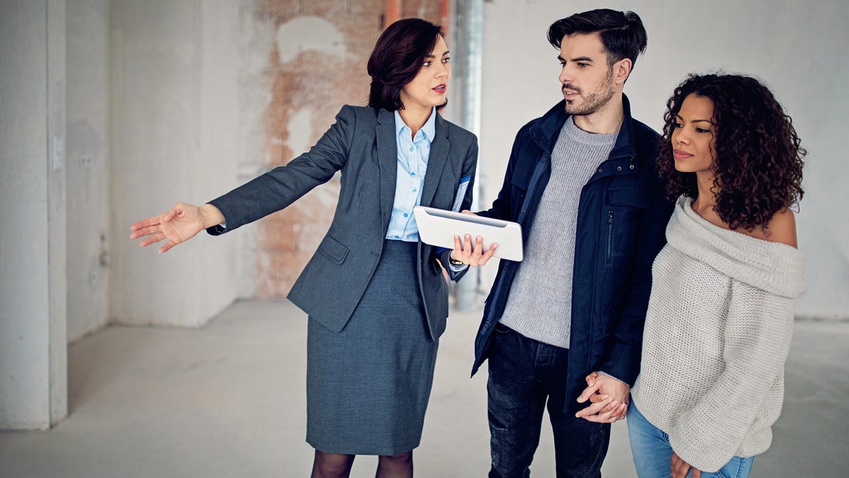 Real estate agent is showing new apartment to a young couple