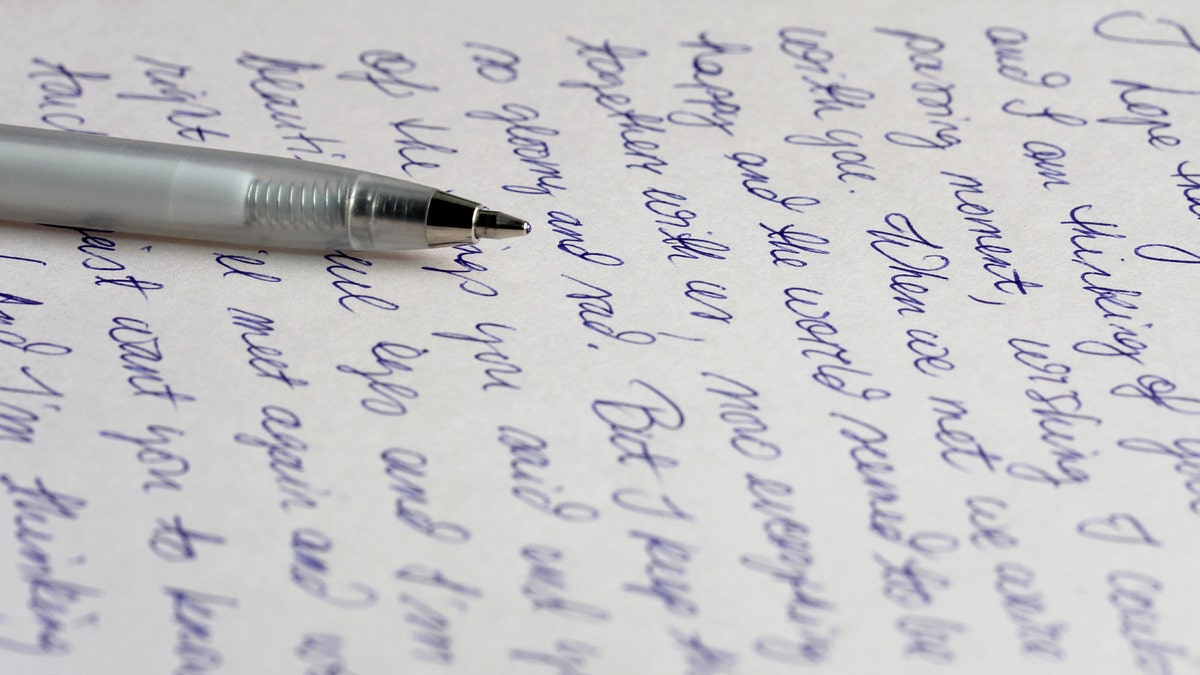 A handwritten letter with a silver ballpoint pen.