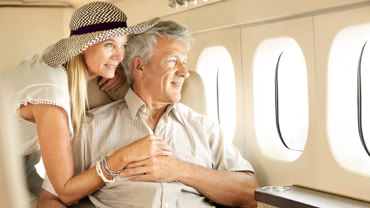 Casal sênior sorridente na janela do avião