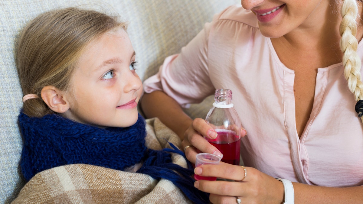 Portrait of woman with liquid medicine and child having influenza