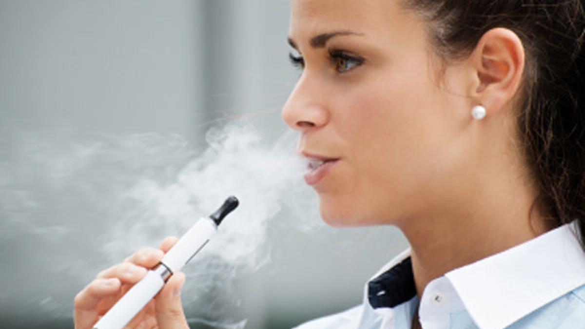 young woman smoking electronic cigarette outdoor office building