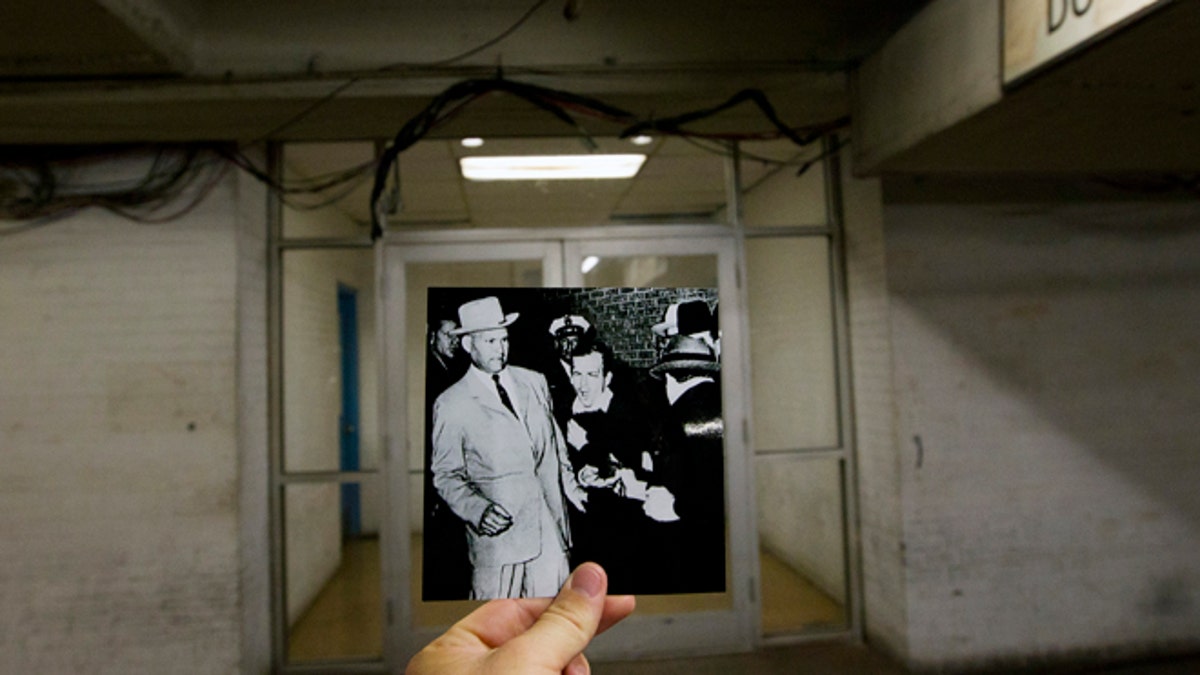 This Sept. 10, 2013 photo shows an image taken by Bob Jackson of the Dallas Times Herald on Nov. 24, 1963, of Lee Harvey Oswald, assassin of U.S. President John F. Kennedy, reacting as Dallas night club owner Jack Ruby, foreground, shoots at him from point blank range in a corridor of Dallas Police Headquarters, juxtaposed with the current scene at the Dallas Police Headquarters, in Dallas. (AP Photo/Houston Chronicle, Cody Duty)
