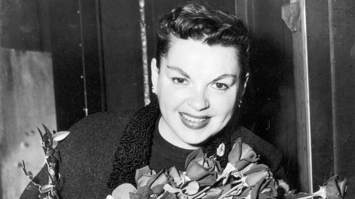 Judy Garland poses with long-stemmed roses in her arms as she arrives in New York City on Sept. 17, 1956.  The singer-actress is to begin rehearsals for her Sept. 26  Palace Theater engagement.  (AP Photo)