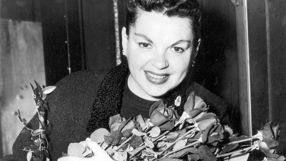 Judy Garland poses with long-stemmed roses in her arms as she arrives in New York City on Sept. 17, 1956.  The singer-actress is to begin rehearsals for her Sept. 26  Palace Theater engagement.  (AP Photo)