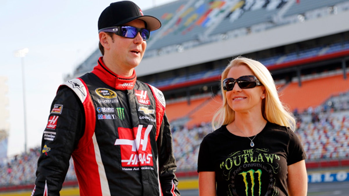 FILE - In this May 22, 2014, file photo, Kurt Busch, left, stands with Patricia Driscoll before qualifying for a NASCAR Sprint Cup series auto race at Charlotte Motor Speedway in Concord, N.C.  Driscoll, the former girlfriend of Busch, has been charged with stealing from a military charity she led. She was indicted on two counts each of wire fraud, mail fraud, and tax evasion, and one count of attempts to interfere with administration of Internal Revenue laws. (AP Photo/Terry Renna, File)