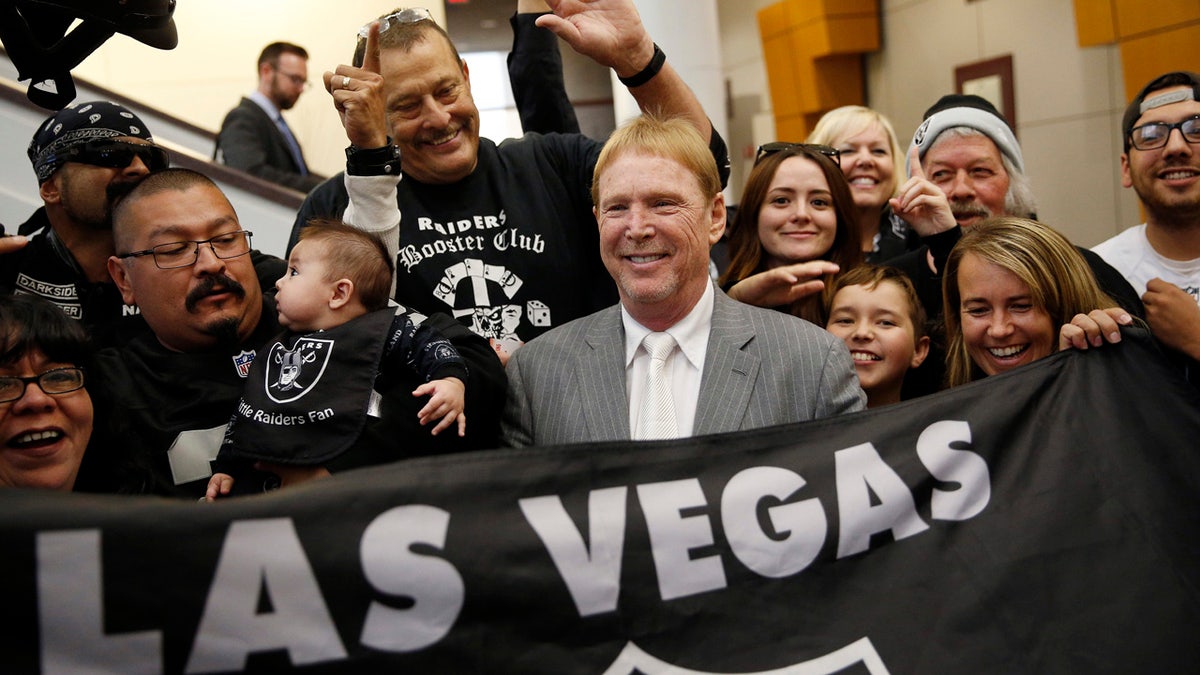 FILE - In this April 28, 2016, file photo, Oakland Raiders owner Mark Davis, center, meets with Raiders fans after speaking at a meeting of the Southern Nevada Tourism Infrastructure Committee in Las Vegas. America's most popular sport is in the midst of its greatest migration in a quarter century. In a little over a year, three NFL franchises have either moved, announced a resettlement or filed paperwork seeking to relocate. (AP Photo/John Locher, File)