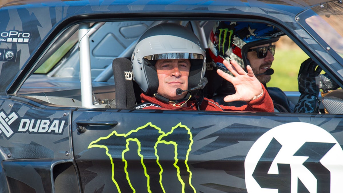 Actor and Top Gear presenter  Matt LeBlanc, left, waves , as he sits with  rally driver Ken Block during filming of BBC Top Gear in Westminster, London on Sunday Sunday March 13, 2016 .