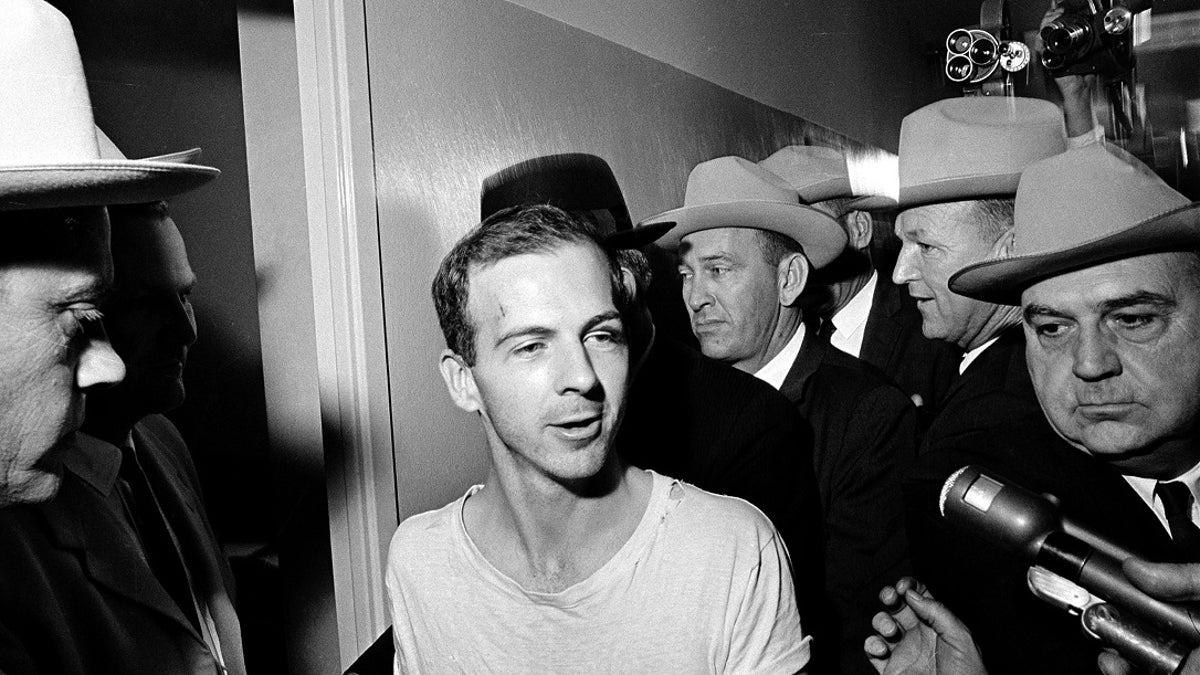 FILE - In this Nov. 23, 1963, file photo, surrounded by detectives, Lee Harvey Oswald talks to the media as he is led down a corridor of the Dallas police station for another round of questioning in connection with the assassination of U.S. President John F. Kennedy. President Donald Trump is caught in a push-pull on new details of Kennedyâs assassination, jammed between students of the killing who want every scrap of information and intelligence agencies that are said to be counseling restraint.  How that plays out should be known on Oct. 26, 2017, when long-secret files are expected to be released. (AP Photo)