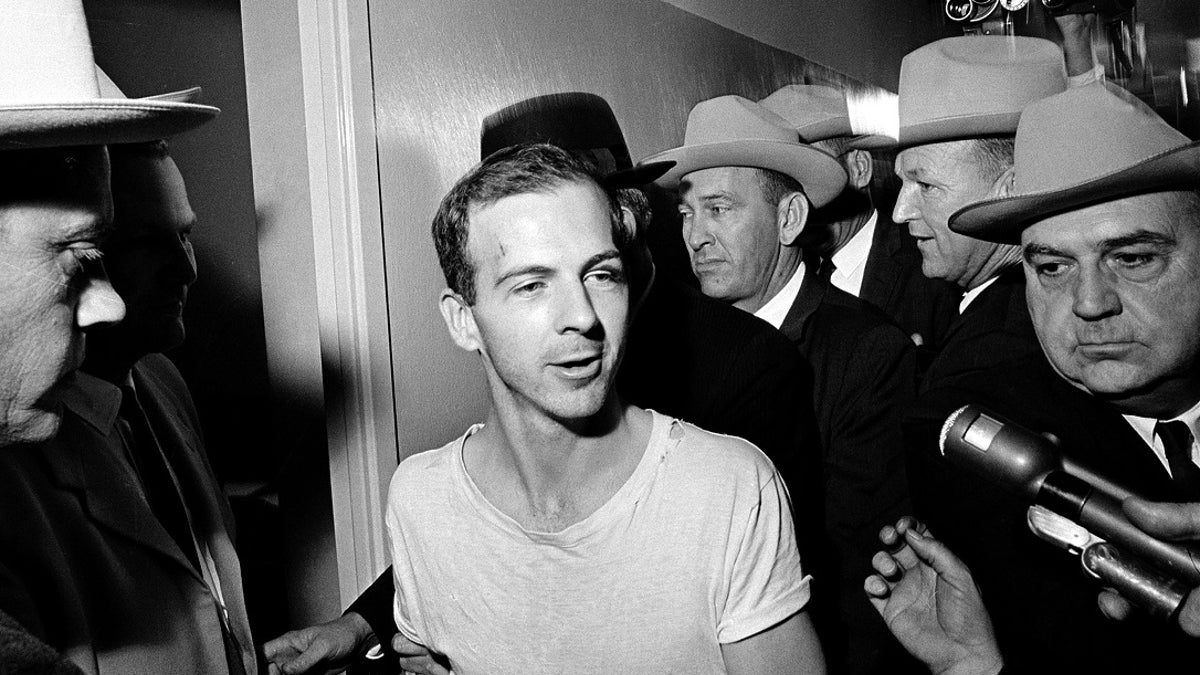 FILE - In this Nov. 23, 1963, file photo, surrounded by detectives, Lee Harvey Oswald talks to the media as he is led down a corridor of the Dallas police station for another round of questioning in connection with the assassination of U.S. President John F. Kennedy. President Donald Trump is caught in a push-pull on new details of Kennedyâs assassination, jammed between students of the killing who want every scrap of information and intelligence agencies that are said to be counseling restraint.  How that plays out should be known on Oct. 26, 2017, when long-secret files are expected to be released. (AP Photo)