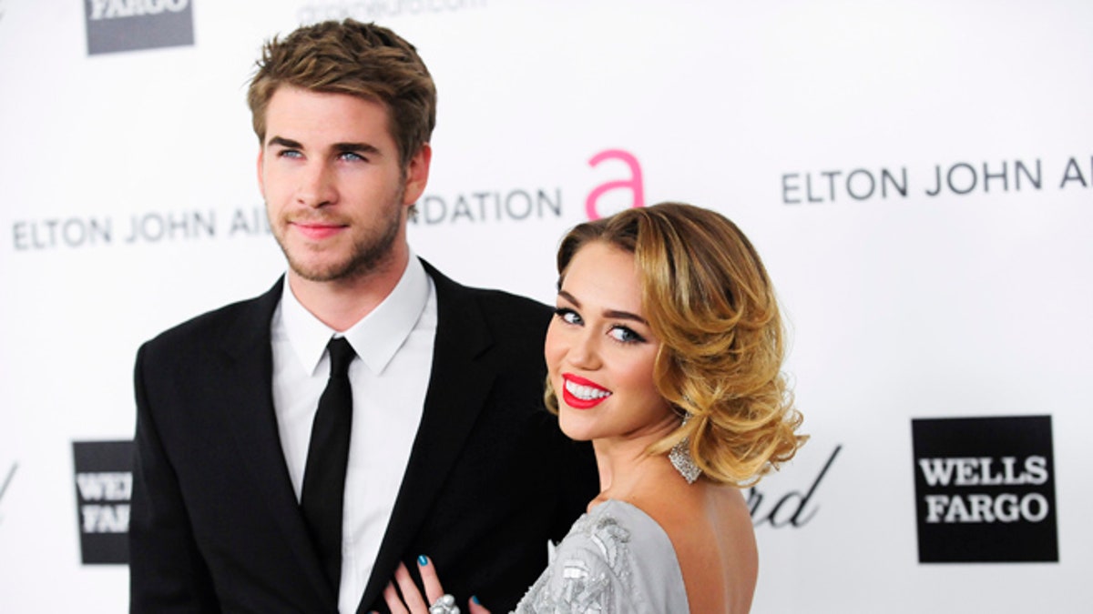 Singer Miley Cyrus (R) and actor Liam Hemsworth arrive at the 20th annual Elton John AIDS Foundation Academy Awards Viewing Party in West Hollywood, California February 26, 2012. REUTERS/Gus Ruelas (UNITED STATES - Tags: ENTERTAINMENT) (OSCARS-PARTIES) - RTR2YJ7I