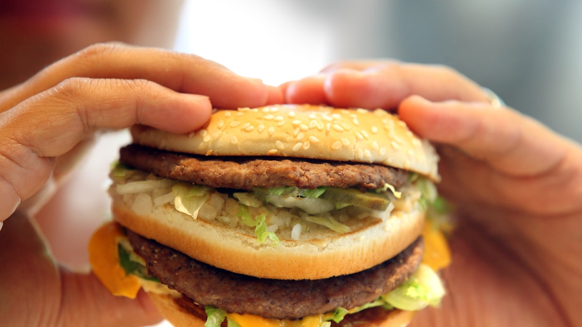 man's hands, holding onto a burger