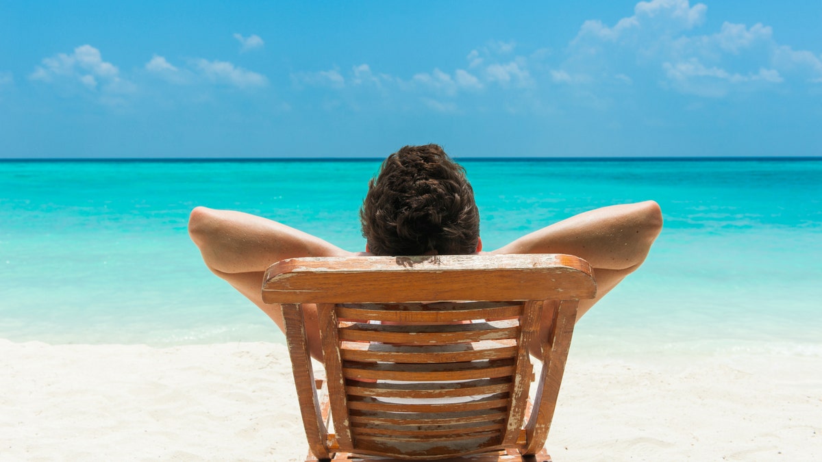 man suntanning sunbathing at beach iStock