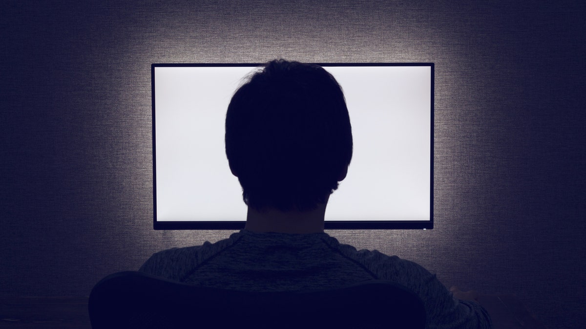 man watching tv in a dark room istock
