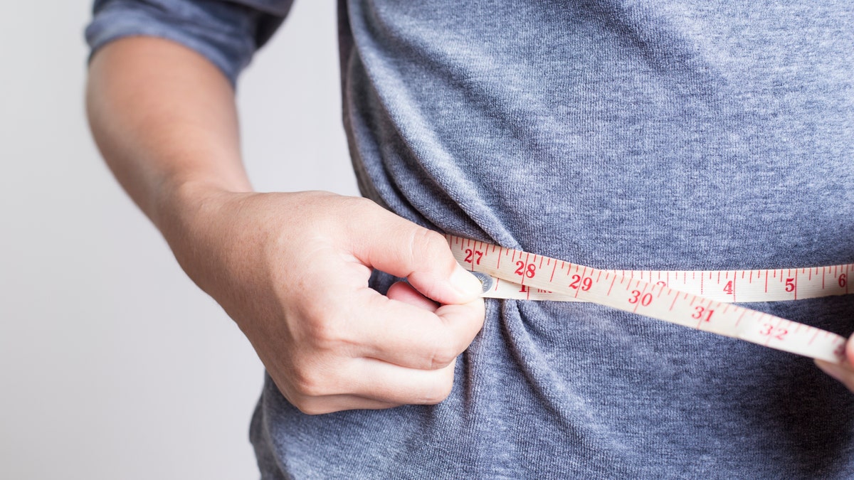 man weight loss measuring tape istock