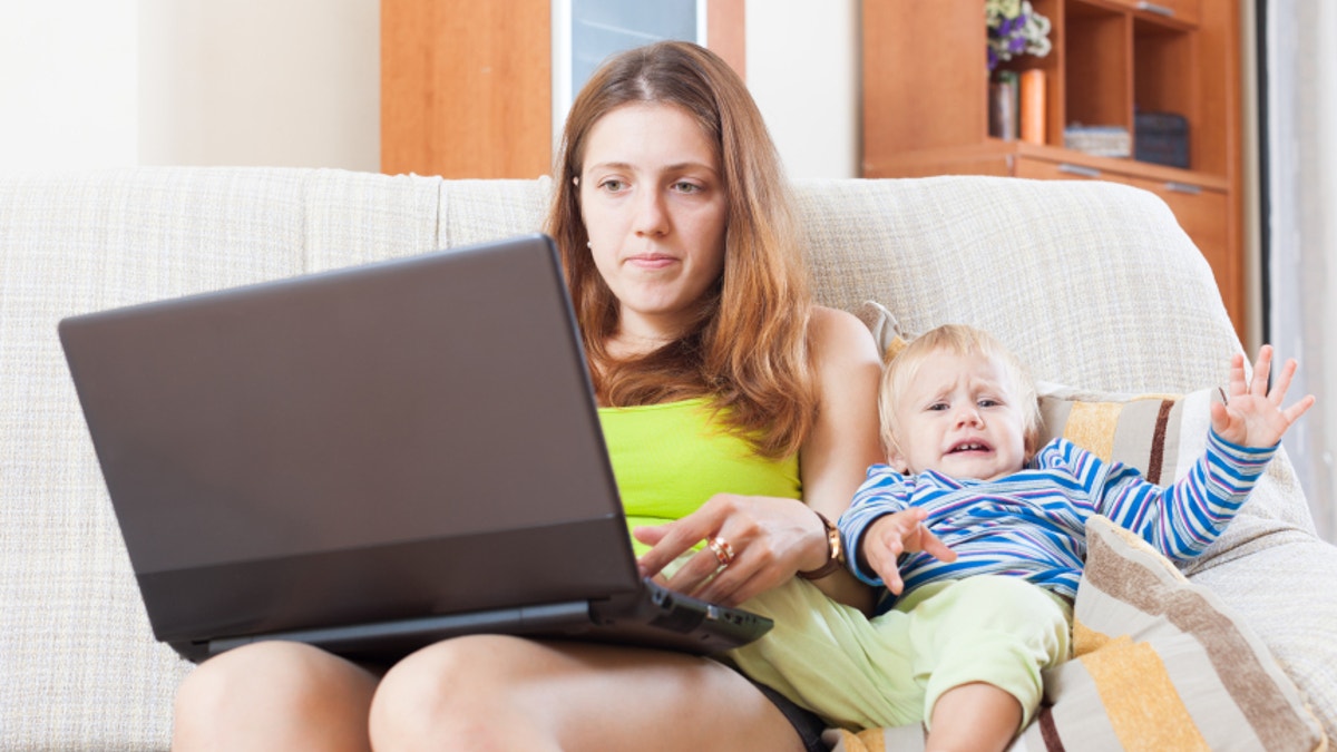 sorehead mother with crying toddler working online